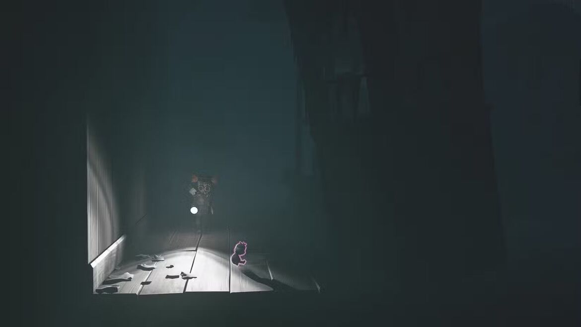 Алон собирает маленькую куклу на полу в тёмном углу в Little Nightmares