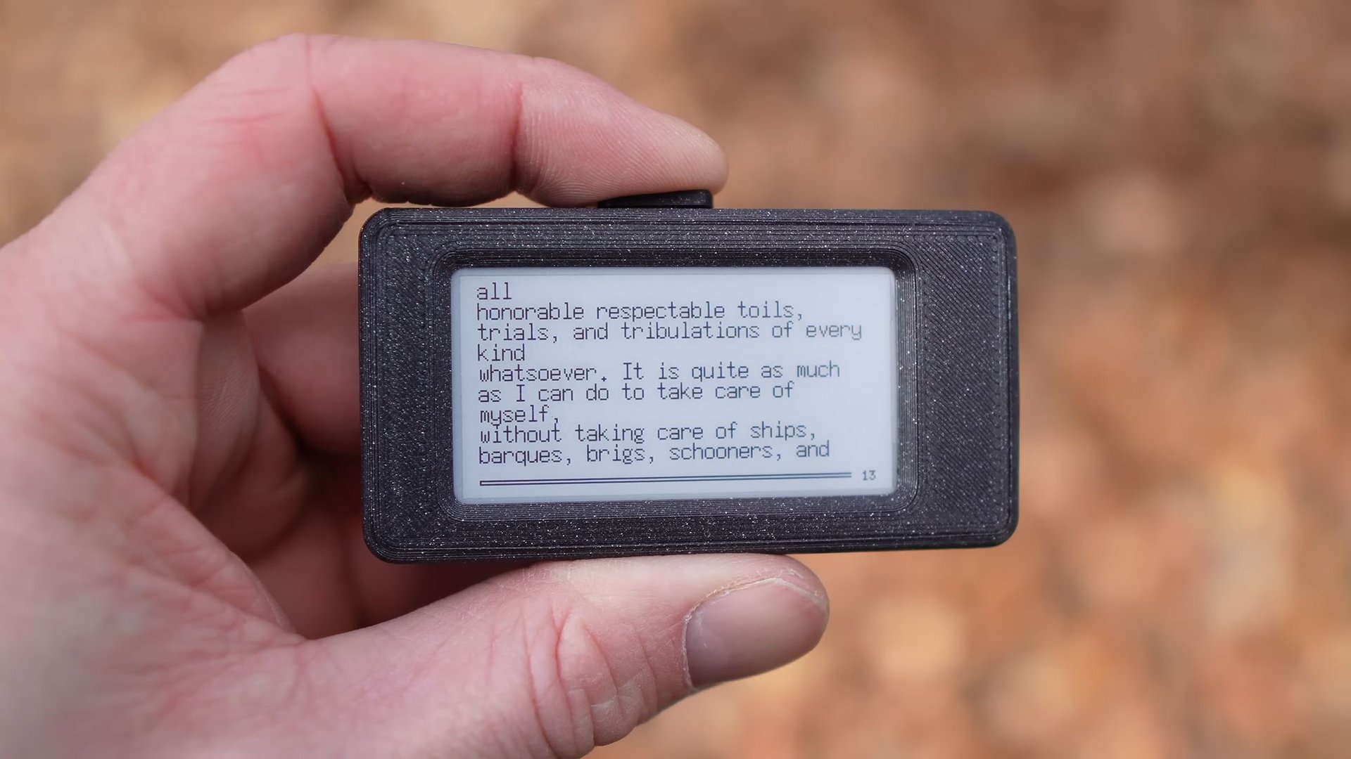 Close up of a hand holding a small e reader displaying a paragraph about honorable toil and ships
