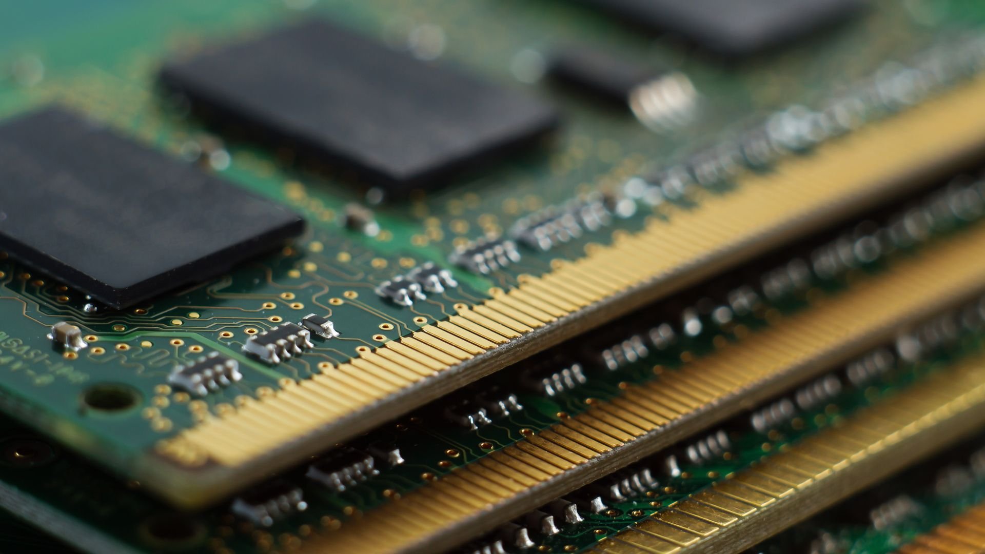 Close up of stacked RAM memory modules showing gold connector pins and black memory chips on a green PCB highlighting computer hardware components