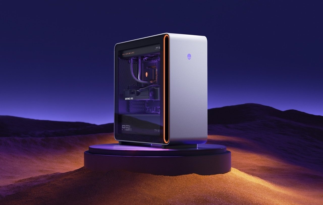Alienware gaming desktop with purple interior lighting on a circular pedestal in a purple desert at dusk