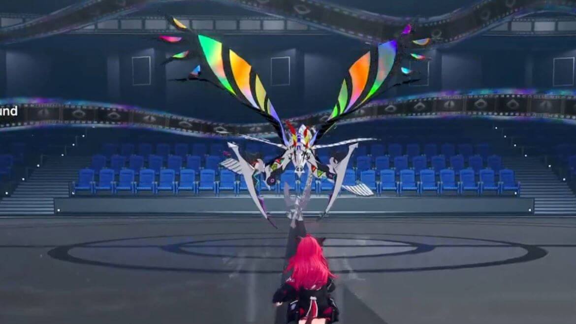 Character with pink hair raises an arm to summon a rainbow winged creature in a circular arena stage behind rows of blue seats