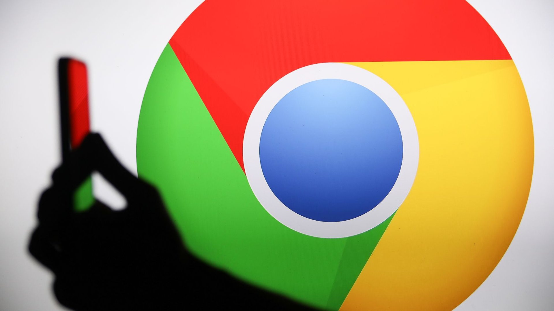 Silhouette of a person taking a photo in front of a large Google Chrome logo