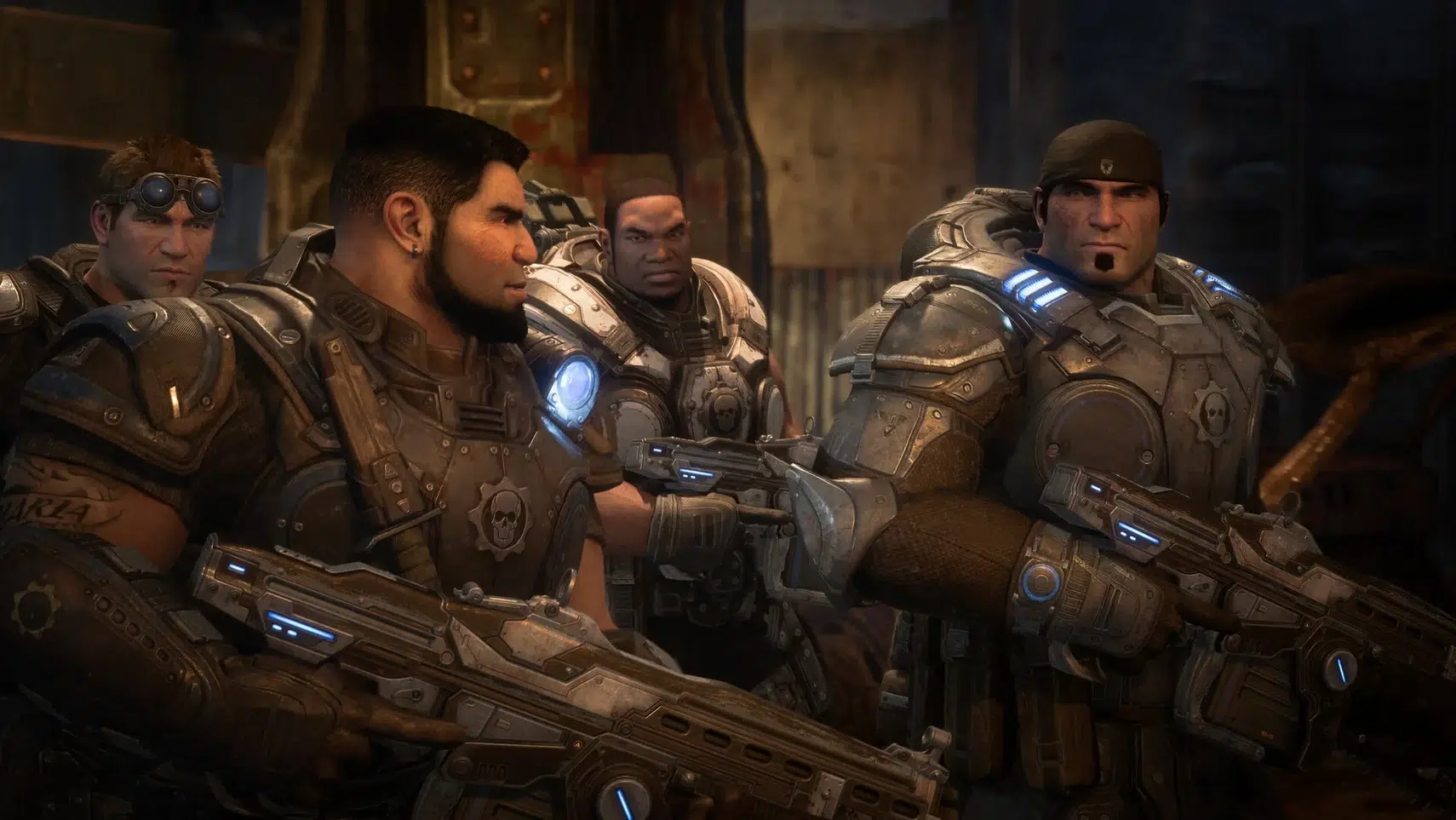 Four heavily armored soldiers with futuristic rifles stand together in a dim industrial setting