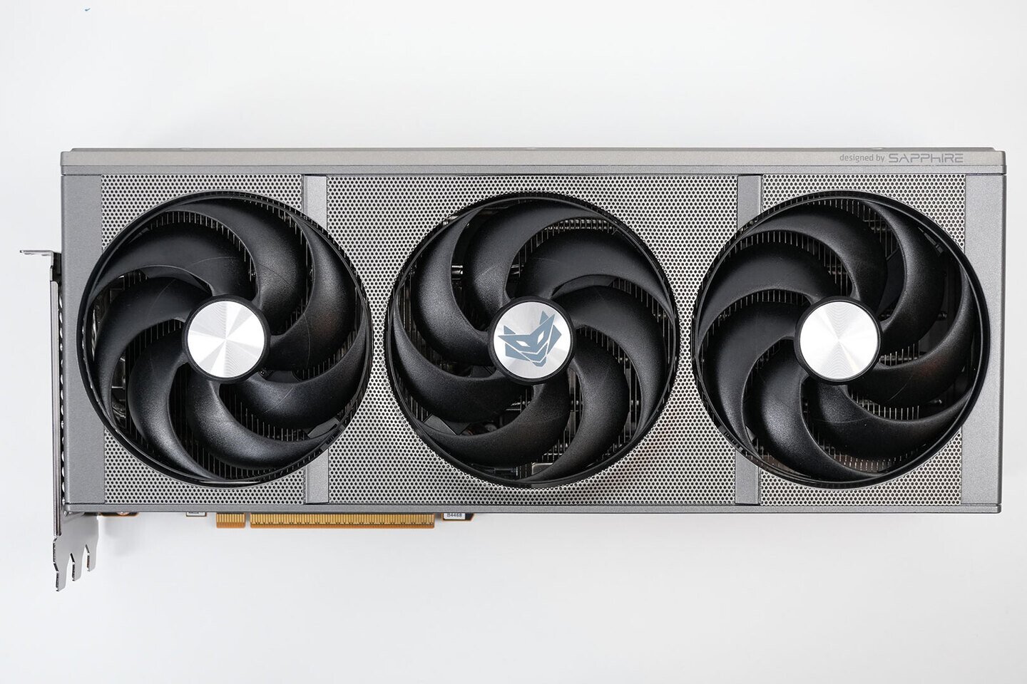 Triple fan graphics card with a perforated metal shroud and PCIe connector visible designed by Sapphire on the right edge