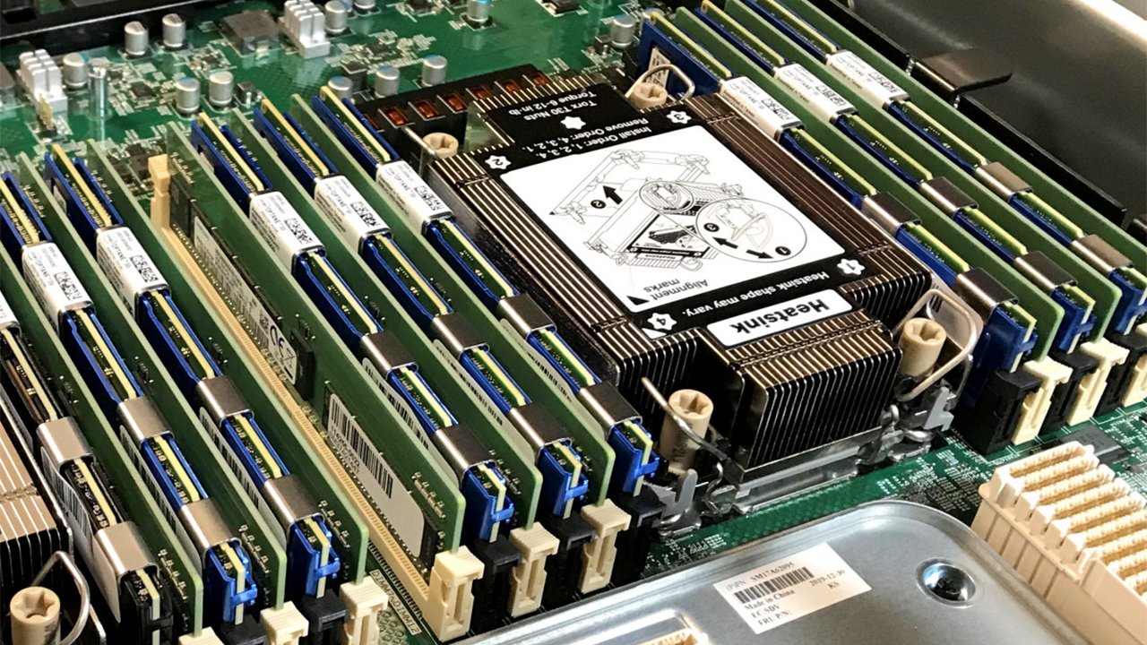 Close up of a server motherboard with RAM modules installed in multiple slots around a central heatsink capacity label visible