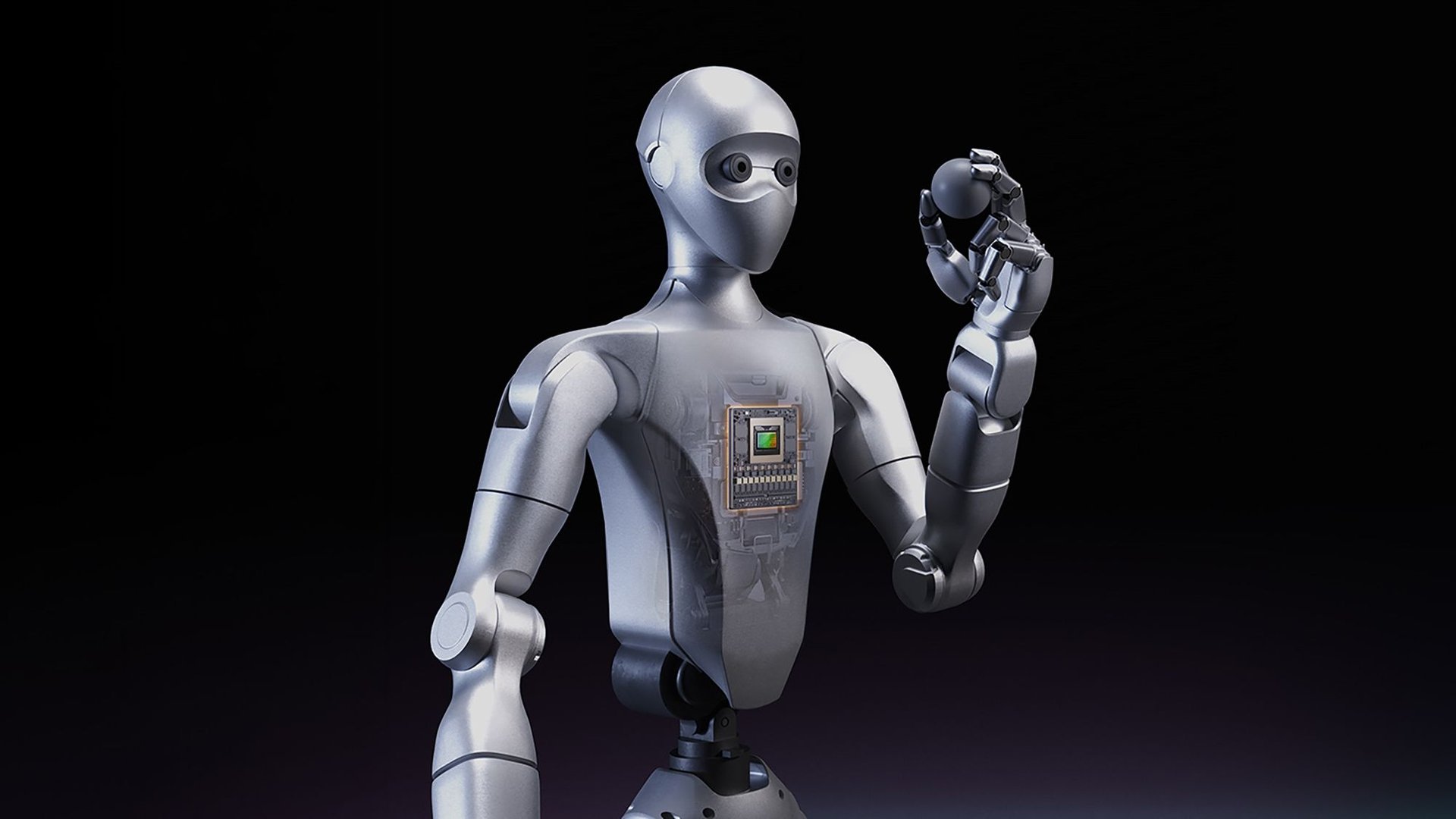 Silver humanoid robot with a visible circuit board in its chest raising its right hand against a black background