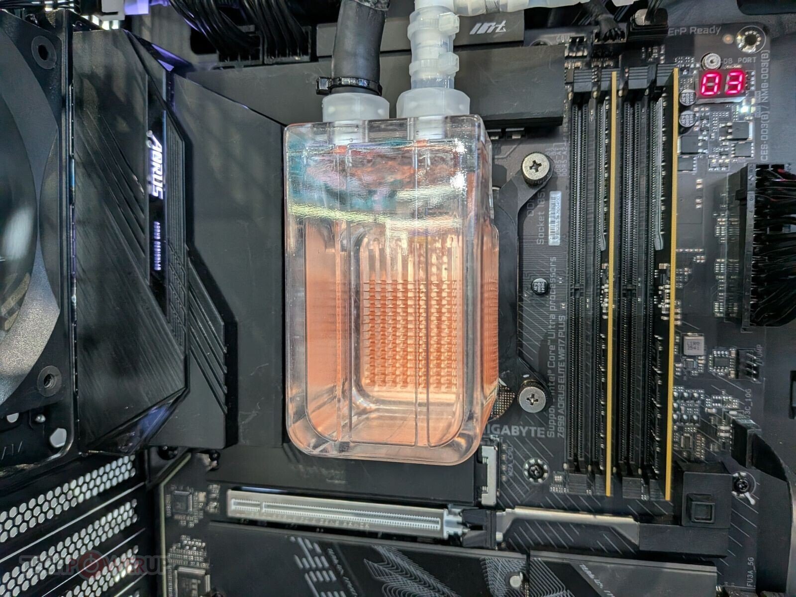 Transparent CPU liquid cooling reservoir with orange coolant connected to tubes mounted on a PC motherboard in a high end build