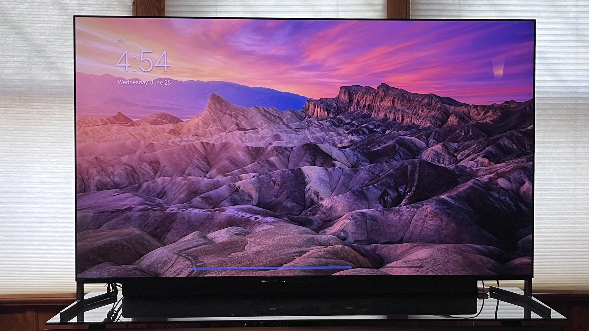 Large flat screen TV displaying a purple sunset over jagged mountains in a desert landscape