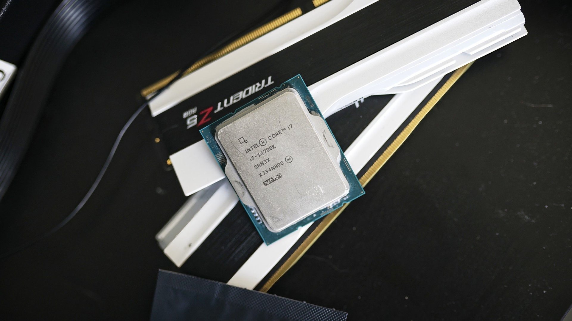 Close up of an Intel Core i7 CPU seated on a motherboard with white RAM modules nearby