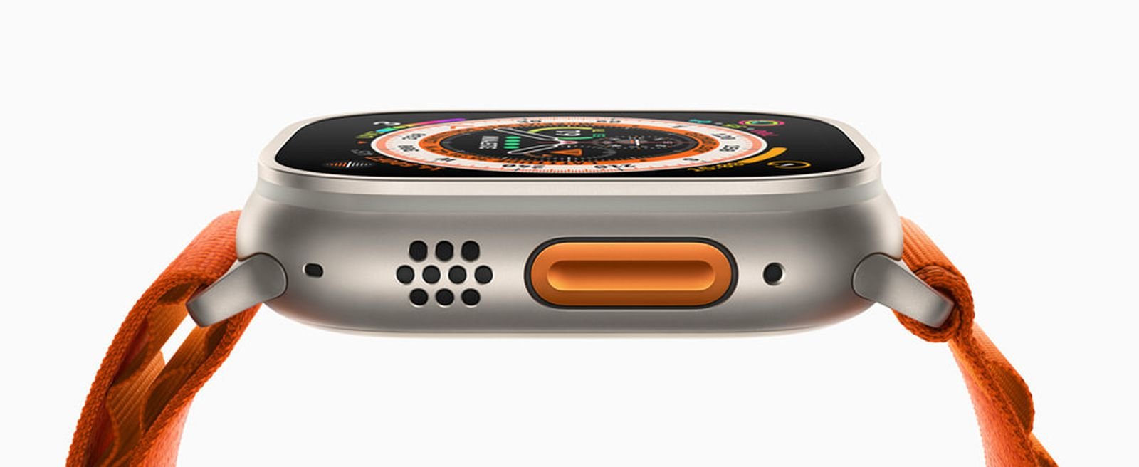 Side view of a smartwatch with an orange strap exposing the speaker holes and an orange oval button on the metal case