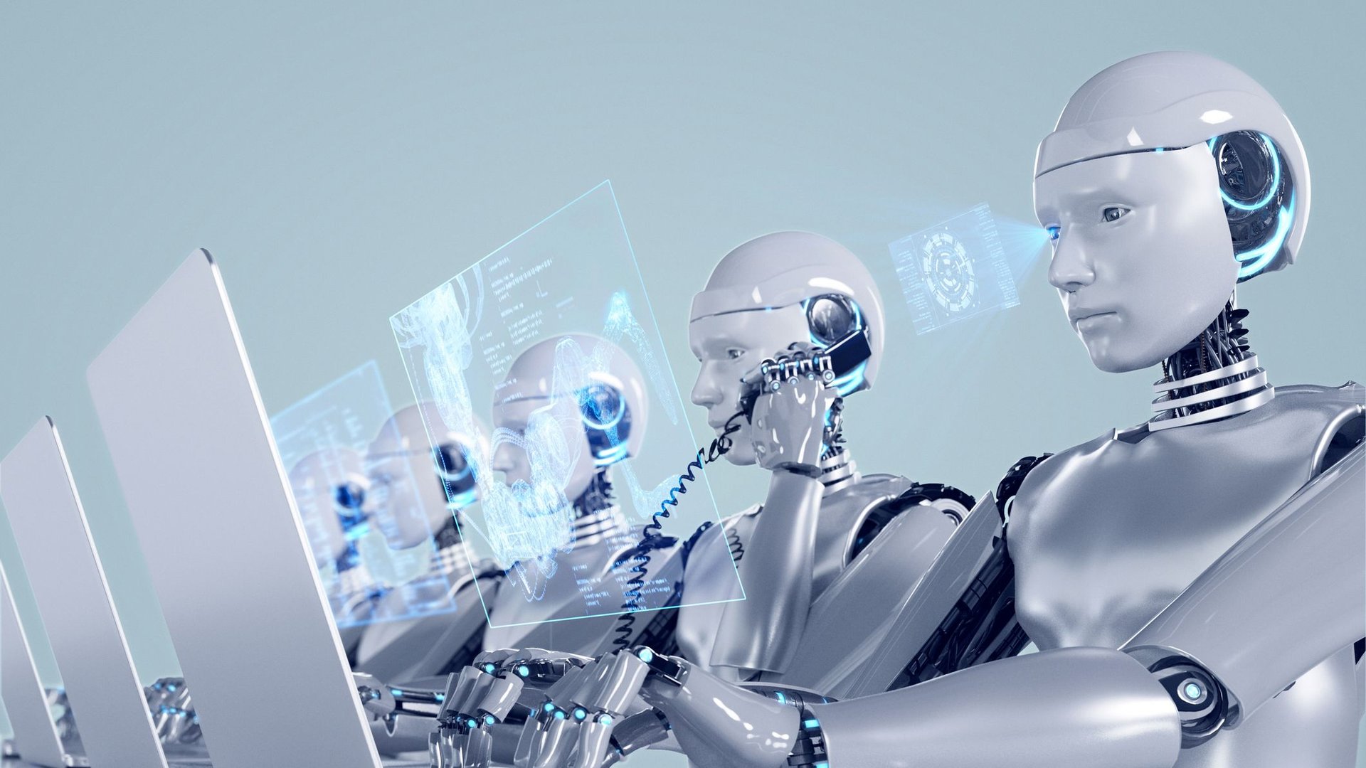 Three silver humanoid robots work at a high tech desk examining glowing holographic screens and laptops