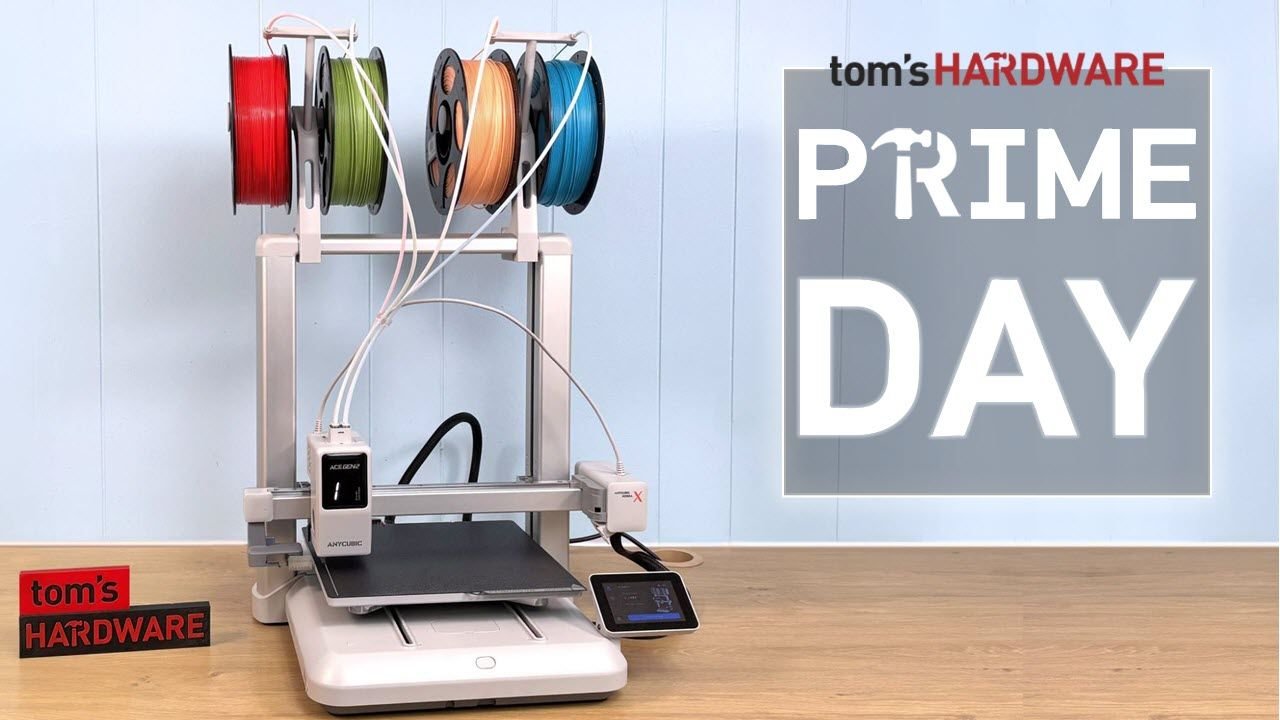 White desktop 3D printer with a filament spool rack and a touchscreen control panel on a wooden table Prime Day banner in the background