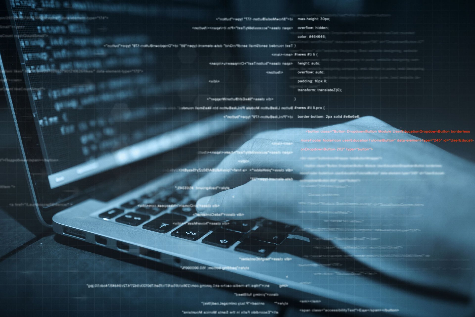 Laptop open with code on the screen and a blue digital overlay suggesting programming or software development