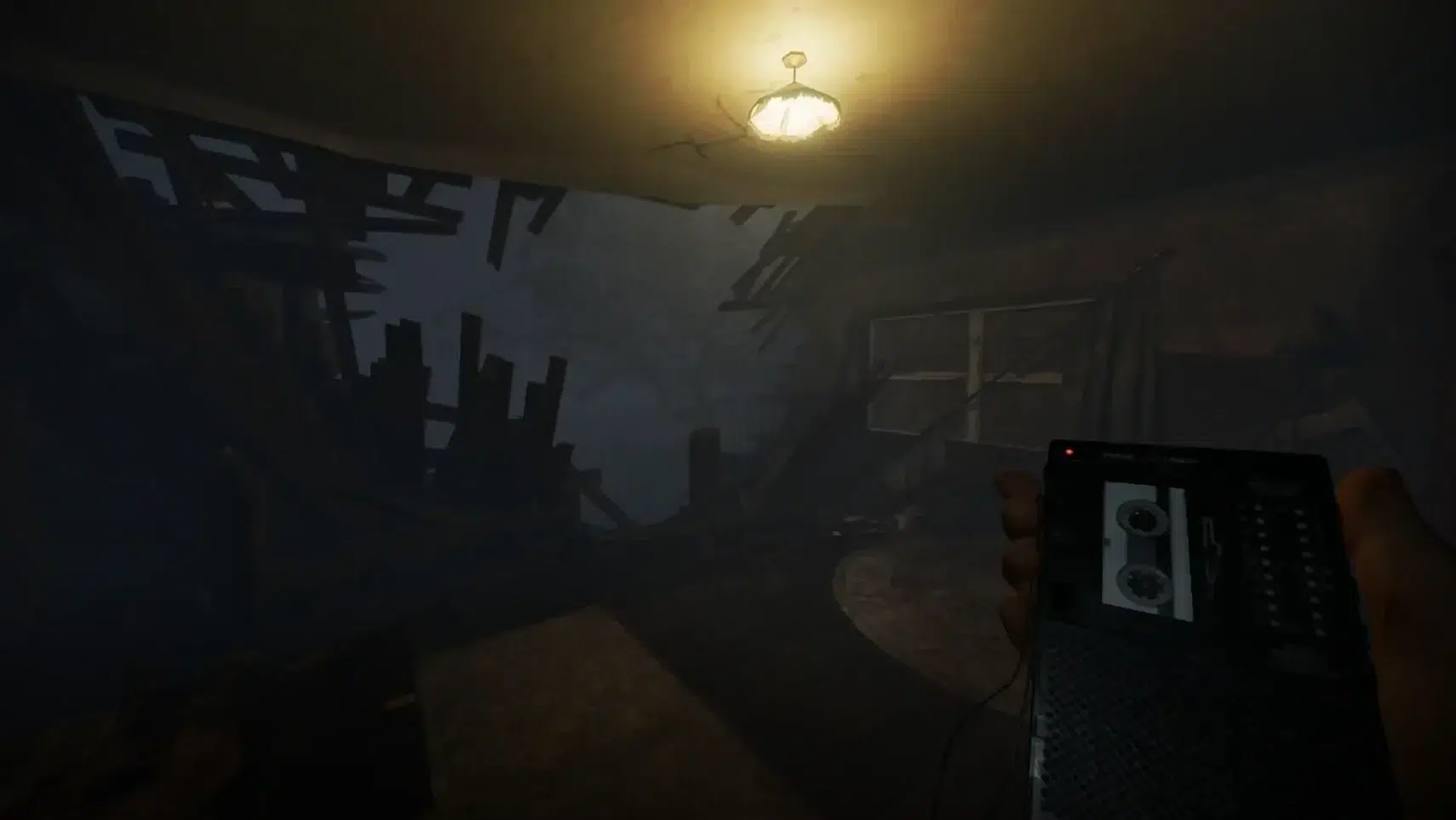 First person view in a ruined basement dim light debris and a hand holding a portable cassette player