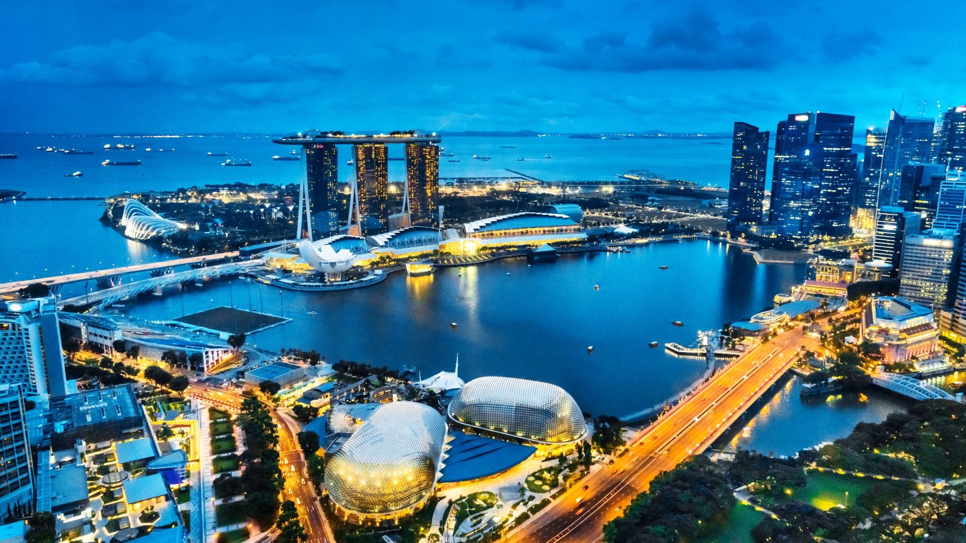 Aerial night view of Singapores Marina Bay with the Marina Bay Sands hotel and futuristic buildings