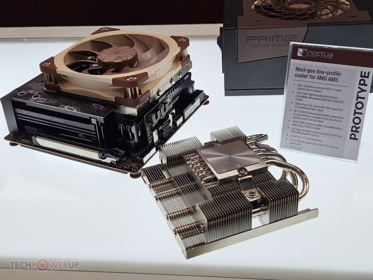 Compact motherboard with a beige Noctua CPU cooler a graphics card and a tall finned heatsink on a white display table