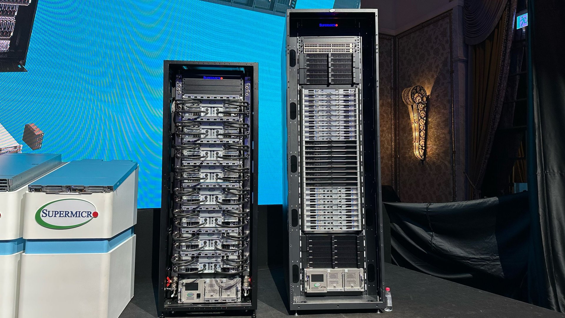 Two tall server racks with densely packed blade servers and cables in a data center setting near a Supermicro branded unit