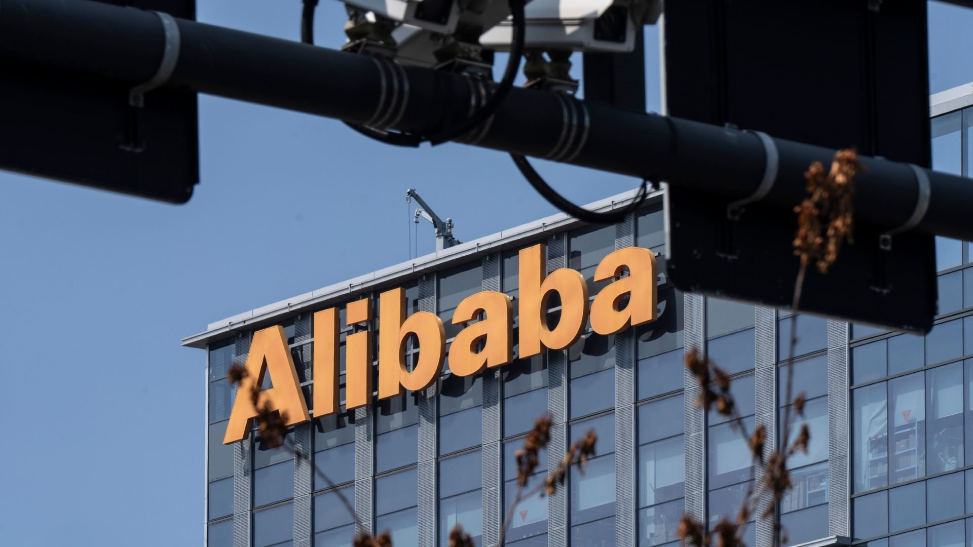 Orange Alphabet sign on a glass fronted office building viewed with dark industrial pipes crossing the foreground