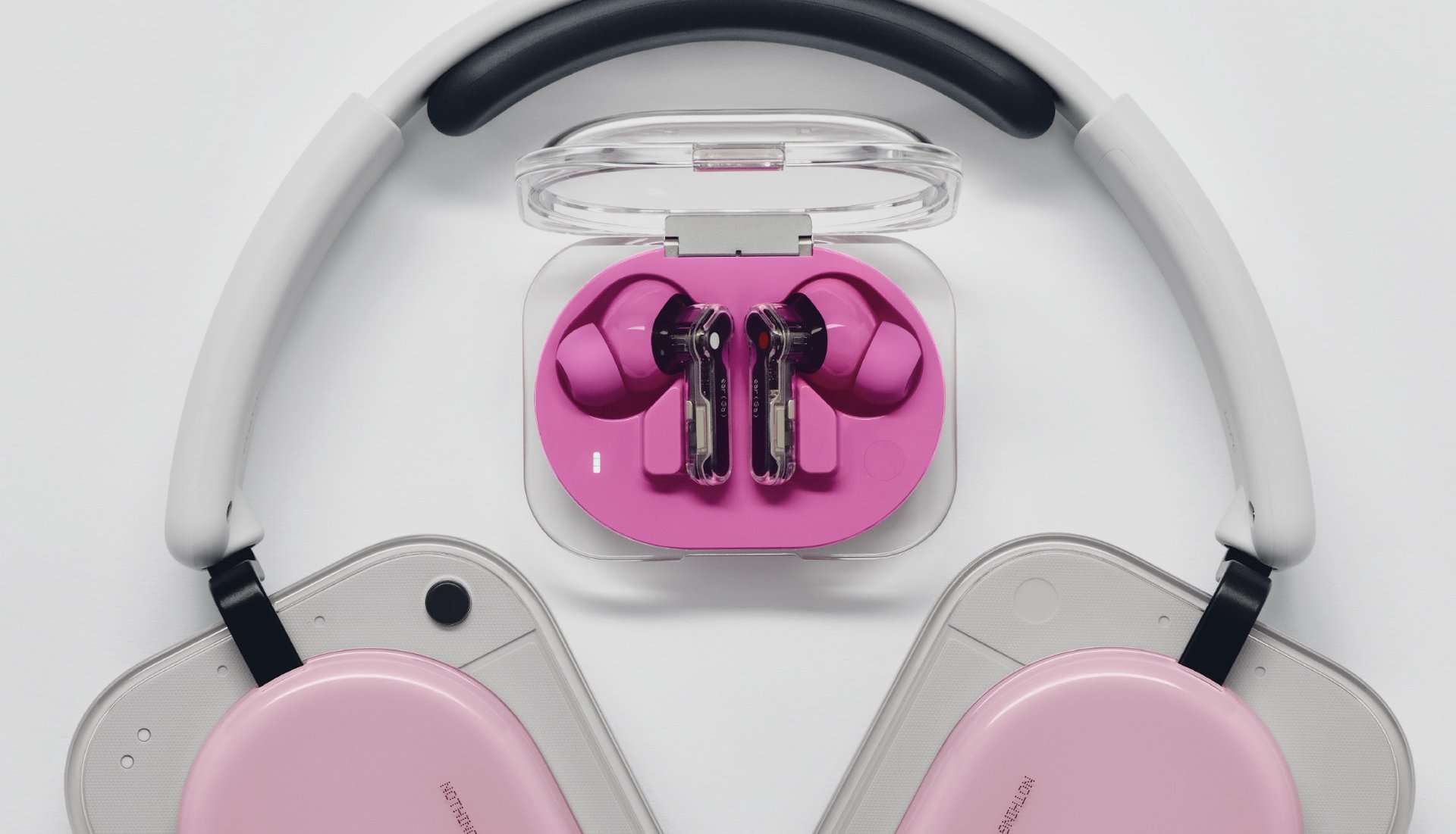 Close up of pink wireless over ear headphones with pink ear cushions on a light gray surface