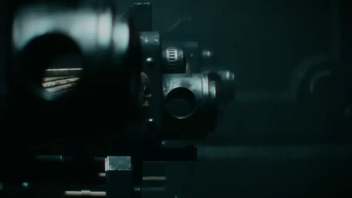 Close up of a precision optical instrument with knobs and lenses in a dark lab setting dimly lit and metallic
