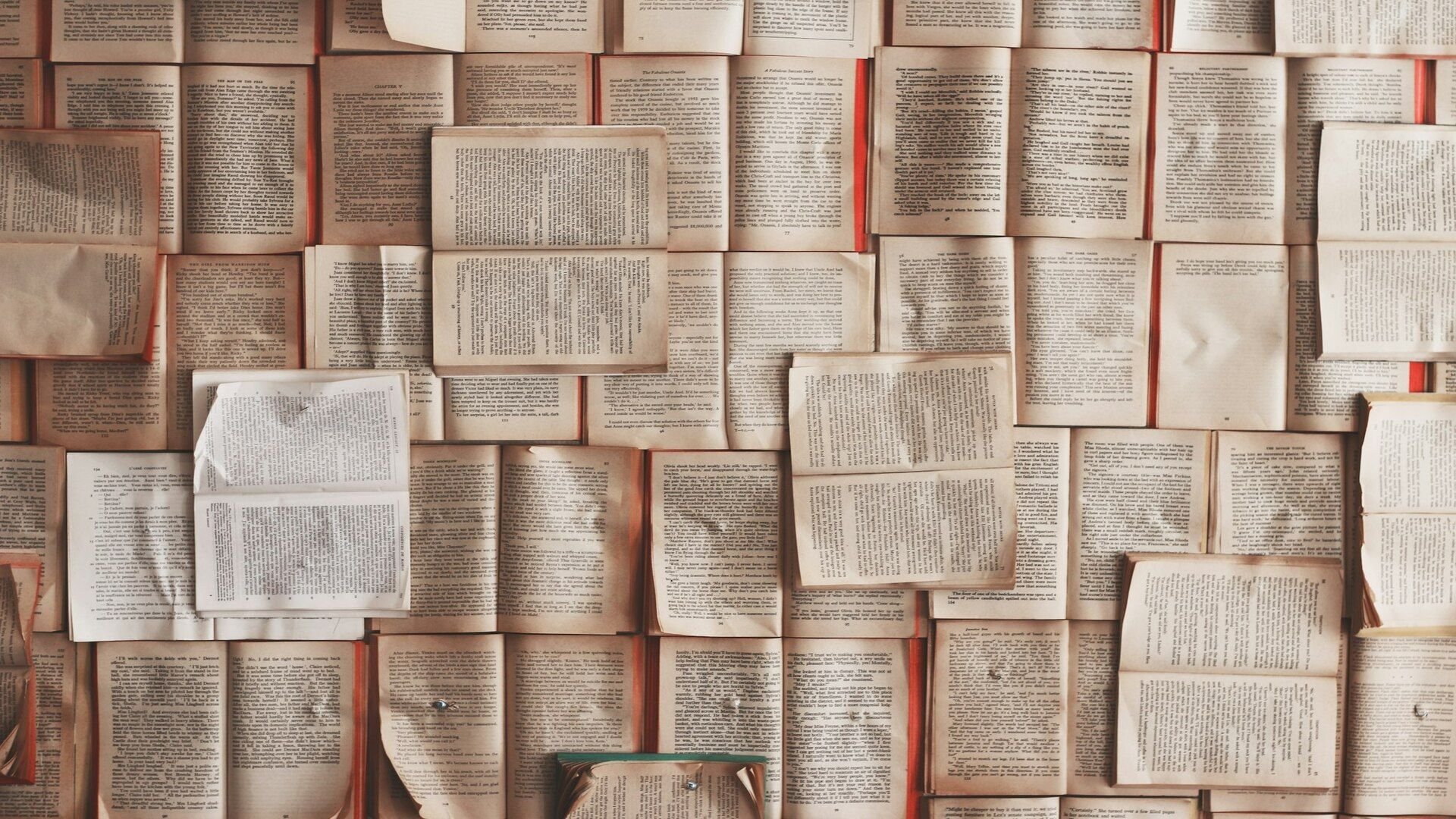 Wall of open book pages arranged in a grid creating a vintage library wall of text